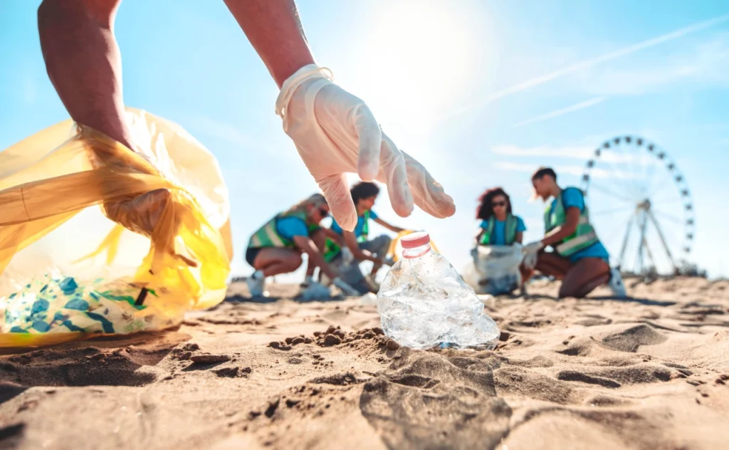 wolontariusze zbierają plastikowe odpady z plaży podczas akcji walki z zanieczyszczeniem plastikiem