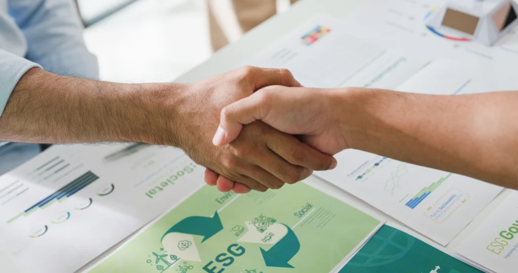 Raport ESG nad którym dwie osoby podają sobie ręce