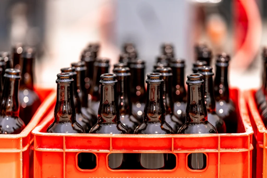 wielorazowe butelki zwrotne ze szkła umieszczone w plastikowej skrzynce transportowej