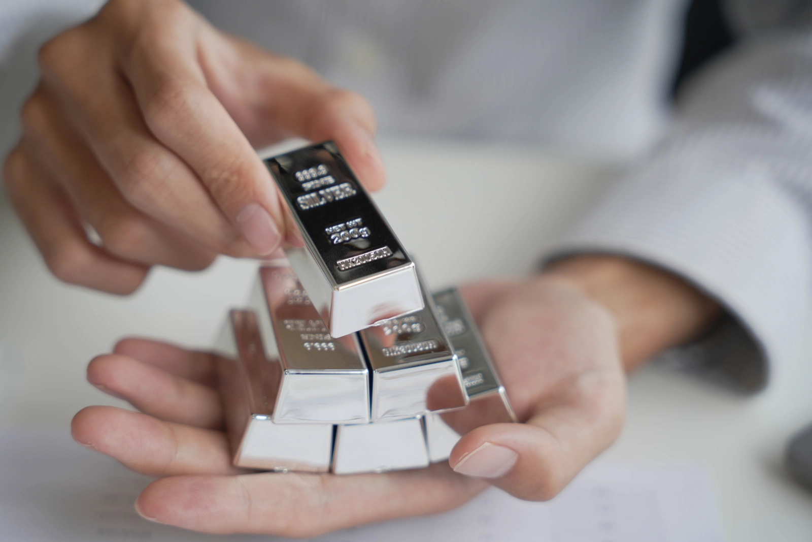 męskie dłonie trzymają sztabki srebra - surowca strategicznego dla polskiej gospodarki