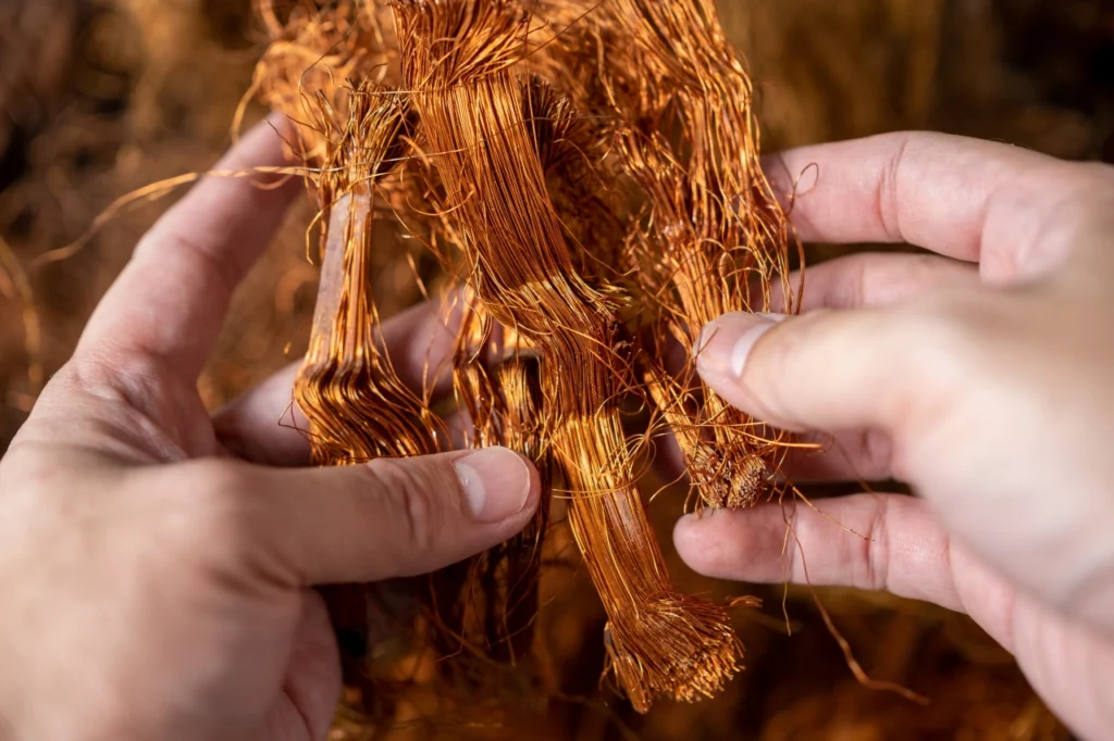 męskie dłonie trzymają zwój miedzianych drutów, z których można odzyskać surowiec krytyczny i strategiczny dla UE: miedź