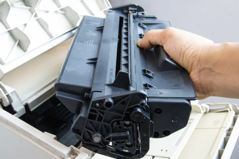 męska dłoń wyjmuje zużyty toner laserowy z drukarki