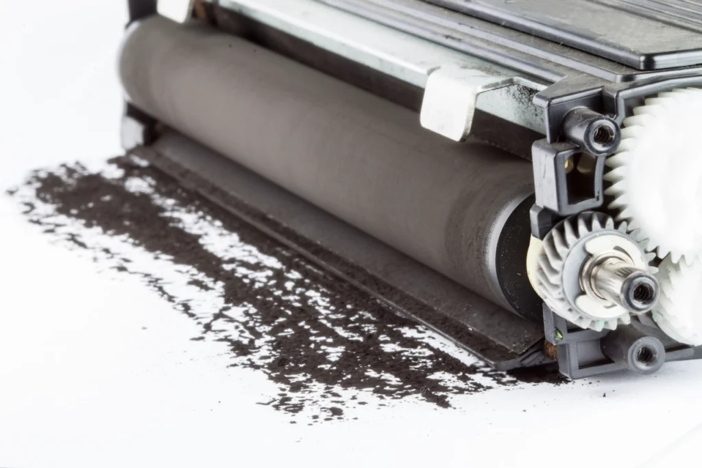 zbliżenie na zabrudzony czarnym proszkiem tonerowym wałek światłoczuły zużytego tonera do drukarki laserowej